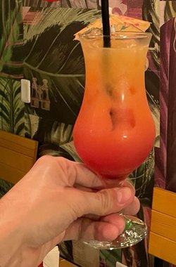 Um drink erguido na frente da parede pintada do salão.