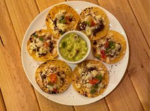 Prato de tostadas em volta de um pote de guacamole.